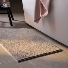 a bathroom with a bathtub, rug and towel on the floor next to it