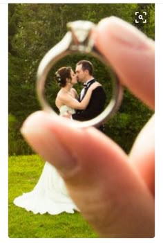 a bride and groom holding their wedding ring in front of the photographer's face