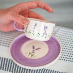 a person is holding a cup and saucer