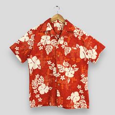 a red hawaiian shirt with white flowers on the front and back, hanging from a hanger