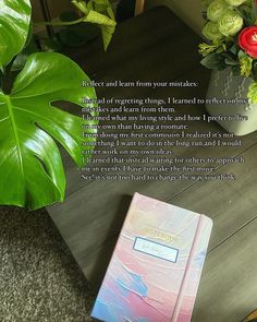 a book sitting on top of a wooden table next to a potted plant