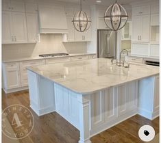 a large kitchen with white cabinets and marble counter tops, an island in the middle