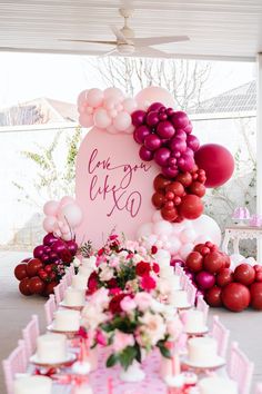 a table topped with lots of pink and red balloons