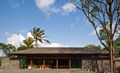 the house is made out of concrete and has grass on the lawn, trees, and steps leading up to it