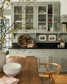 a kitchen with green cabinets and wooden table