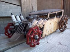 an old toy car made out of forks and wrenches sitting on top of a piece of wood