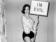 a woman holding a sign that says i'm evil