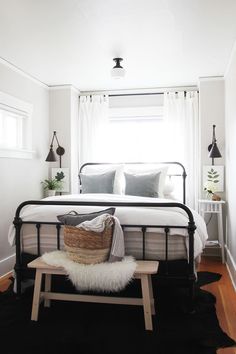 a bedroom with white walls and black metal bed frame in the corner, along with a bench