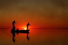 two men fishing at sunset on a small boat