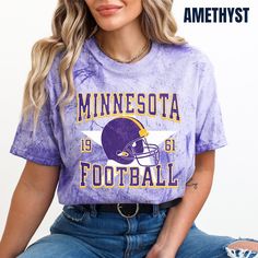 a woman sitting on the ground wearing a minnesota football shirt