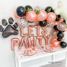 a party table with balloons, cake and cat's paw balloon garland on it