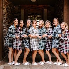 a group of women standing next to each other in matching dresses and slip on shoes