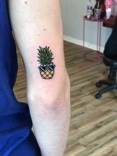 a small pineapple tattoo on the left inner arm, with shades drawn on it