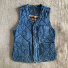 a blue jean vest sitting on top of a bed