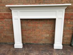 a white fireplace surround in front of a brick wall