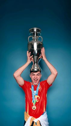 a man holding up a silver trophy on top of his head in front of a blue background