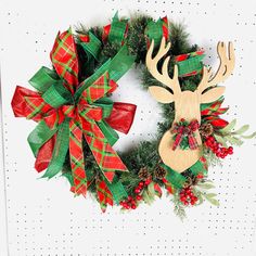 two christmas wreaths with deer heads and red bows on white wall background, decorated with greenery