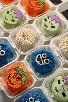 an assortment of decorated cupcakes in plastic containers with faces and eyes on them