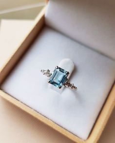 an engagement ring is in a box on a white surface with a blue topaz stone