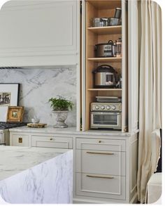 a kitchen with white cabinets and marble counter tops, along with an open shelf above the stove