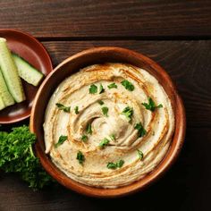 hummus with cucumbers and parsley in a bowl on a wooden table