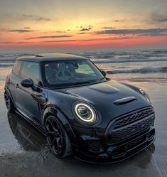 a black mini cooper on the beach at sunset