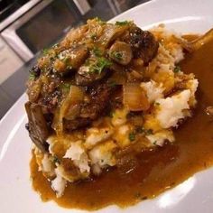 a white plate topped with mashed potatoes covered in gravy and mushroom sauce