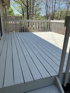 a white wooden deck with railing and trees in the background