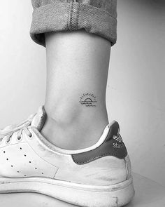 a woman's foot with a small tattoo on her left ankle and the sun behind it