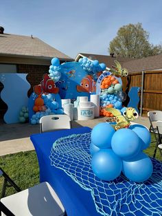 a blue table topped with balloons next to an ocean themed cake and cupcakes