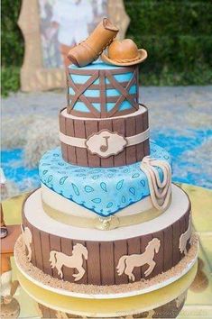 a three tiered cake with cowboy themed decorations