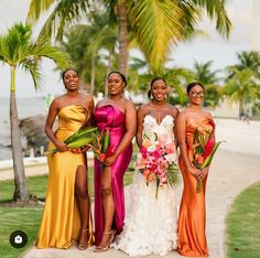 four beautiful women standing next to each other in front of palm trees and the ocean