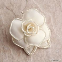 a white flower with pearls on it sitting on top of a cloth covered tablecloth