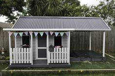 a small gray and white shed sitting in the grass