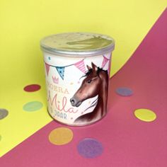 a cup with a horse on it sitting next to a polka dot table cloth and confetti