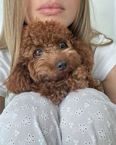 a woman holding a brown poodle in her lap and looking at the camera with an intense look on her face