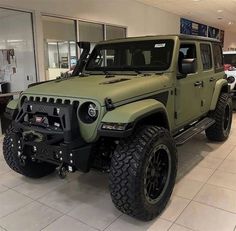 a green jeep is parked in a showroom