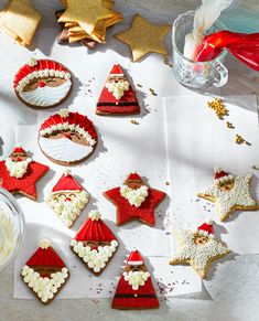 decorated cookies are arranged on a table with other holiday decorations and decorating supplies around them