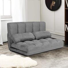 a gray couch sitting on top of a rug in a living room next to a book shelf