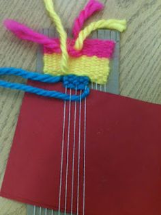 a red piece of paper with some blue and yellow yarn on it