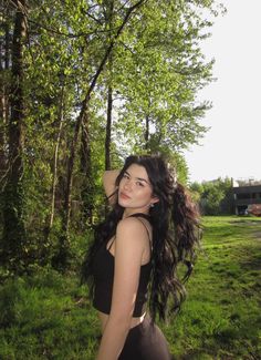 a woman with long hair standing in the grass