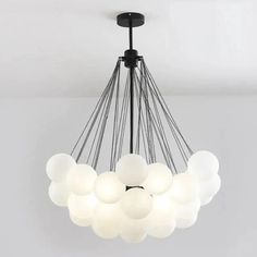 a chandelier with white balls hanging from it's black metal frame and light fixture