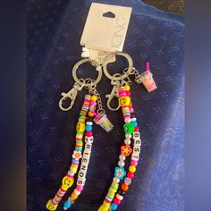 two key chains with beads and smiley faces on them are sitting on a blue towel