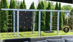 an outdoor play area with swings, climbing bars and a tire swing in the grass