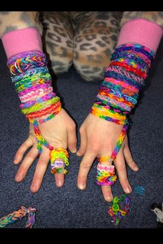 two hands with multicolored bracelets on them