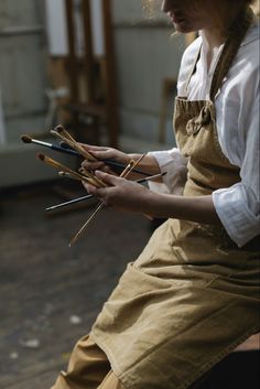 a woman sitting on a bench holding knitting needles