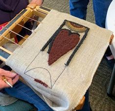 a woman is sitting on the floor working on a piece of art that looks like a heart