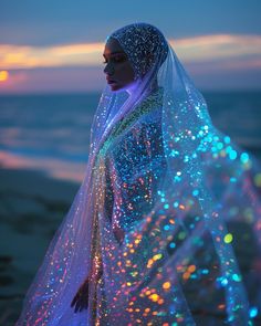 a woman wearing a veil and standing on the beach at night with colorful lights all over her