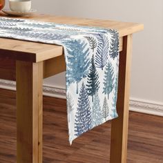 a wooden table topped with a blue and white butterfly print table runner next to a bowl of fruit