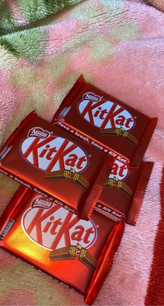 three kitkat chocolate bars sitting on top of a pink blanket